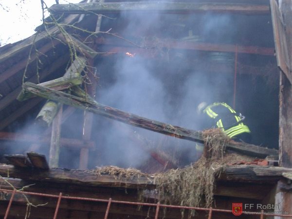 Bild 2 von 2 Mit Heugabeln bewaffnet warfen die beiden Feuerwehrmänner mit Atemschutz (ganz oben) das glühende Heu in das Stockwerk darunter. Oben in der Mitte ist ein Glutnest zu sehen.